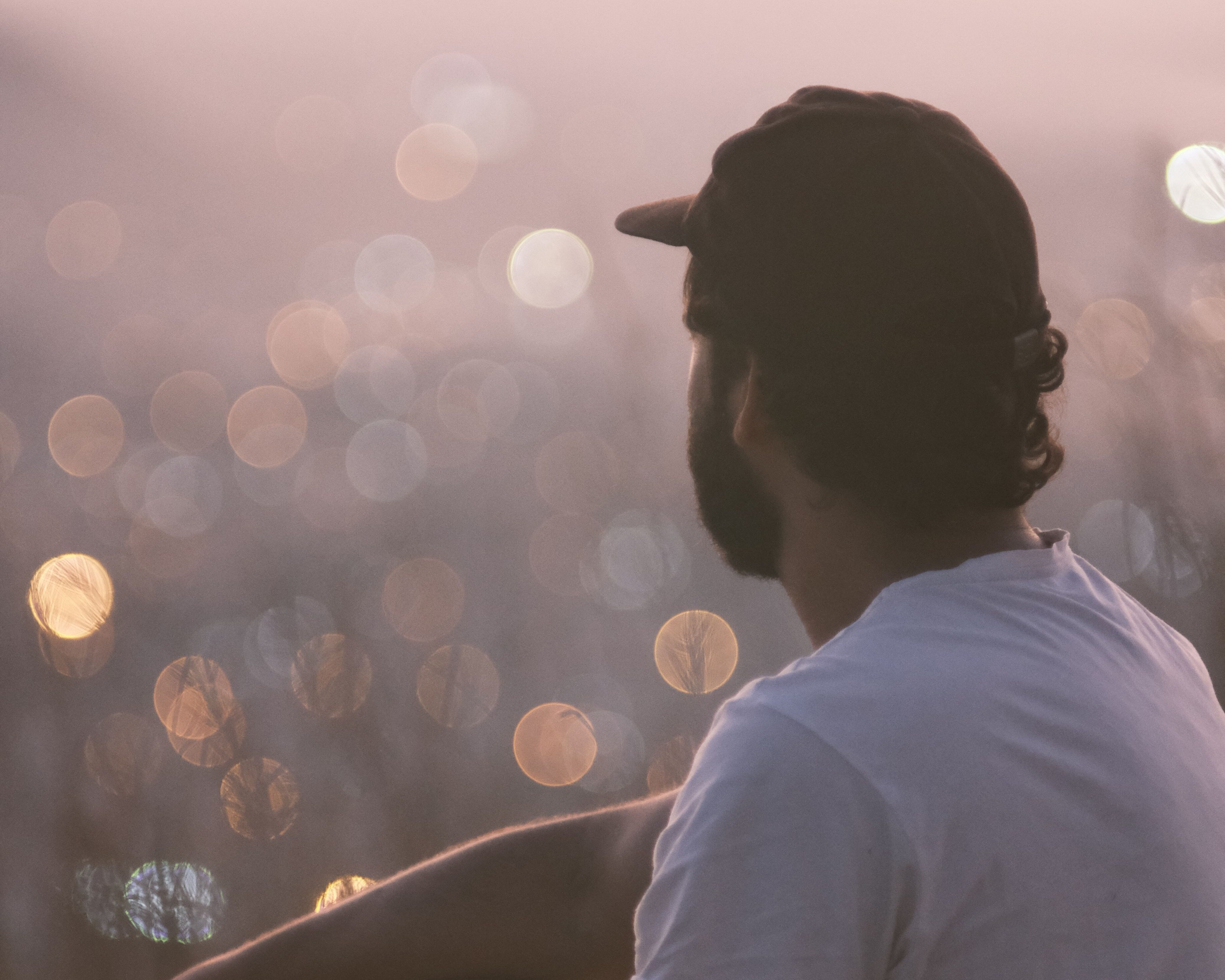 Man overlooking out of focus city lights